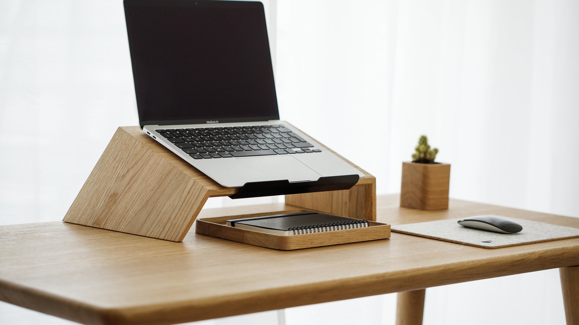 wooden laptop stand on a wooden desk