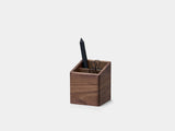 Wooden pen holder with a black pen on a light gray background| walnut
