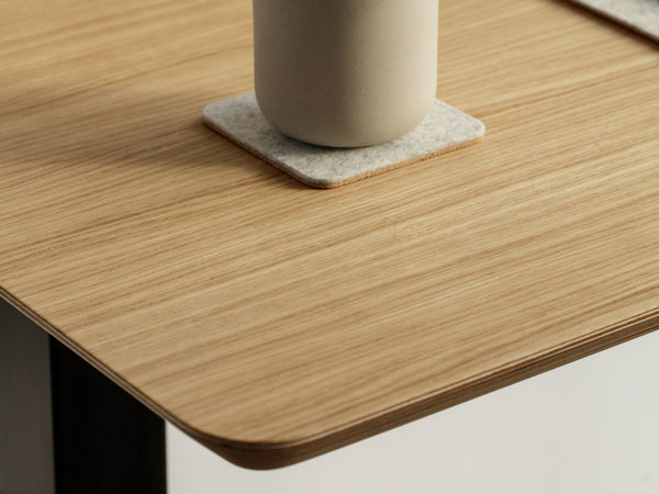Dark wood desk with single angled leg visible, close-up of surface edge.