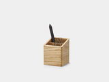 Wooden pen holder with a black pen on a light gray background| oak
