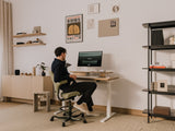 Person sitting at a desk in a home office setting with a computer monitor. |light oak, , 