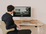 Person sitting at a desk with a Mac mini computer and apple display studio monitor displaying an image of a house. |light oak, , 