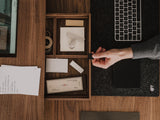 Person organizing items in a wooden desk organizer with a laptop and papers on a wooden desk. | walnut, 