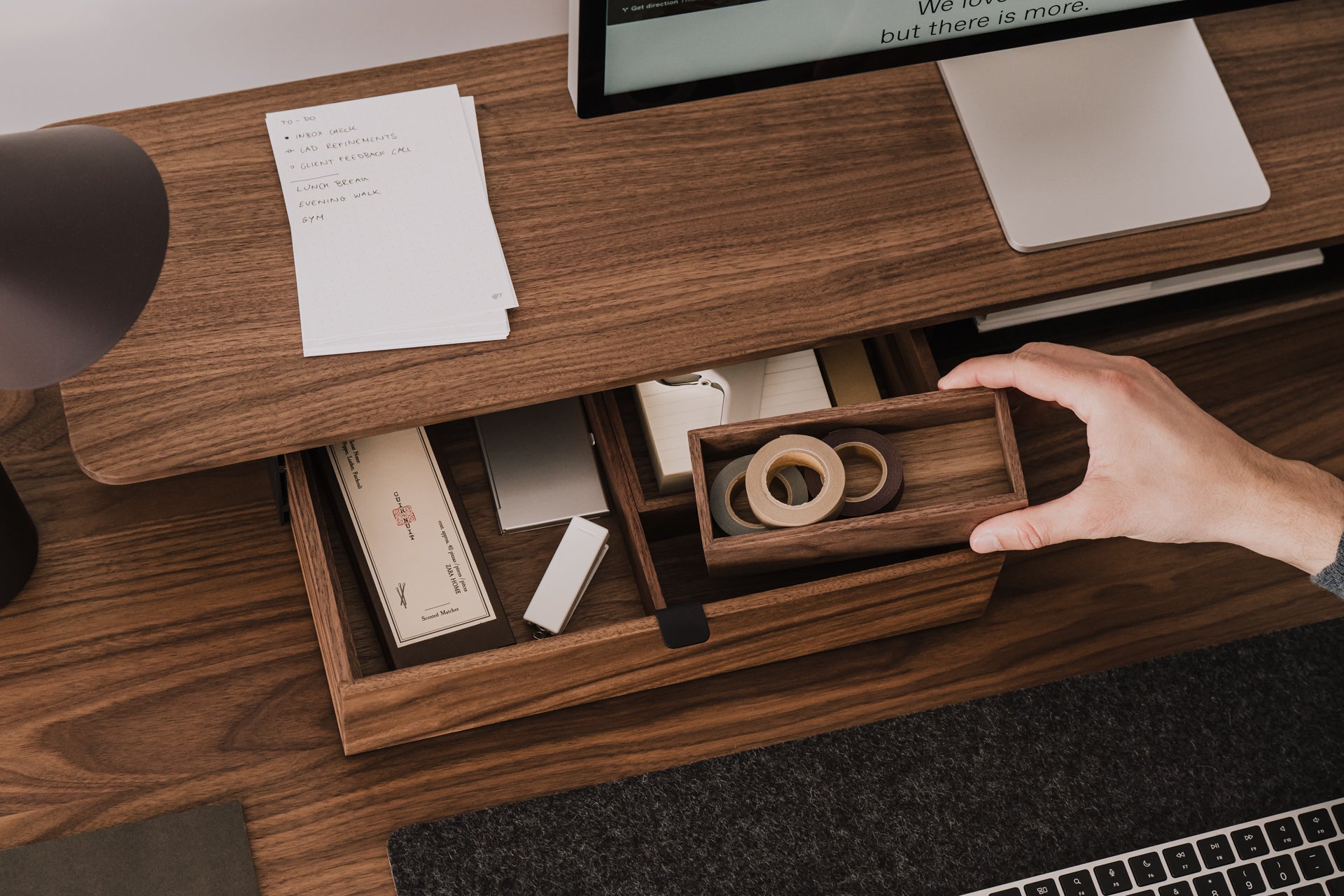 Hand reaching for a wooden desk organizer on a wooden desk with office supplies. | walnut, 