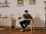 Person sitting at a desk with a laptop in a home office setting | light oak,