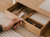 Hand placing a small object into a modular drawer organizer with compartments.| oak, 