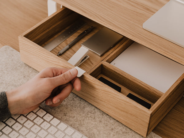 Hand placing a small object into a modular drawer organizer with compartments.| oak, 