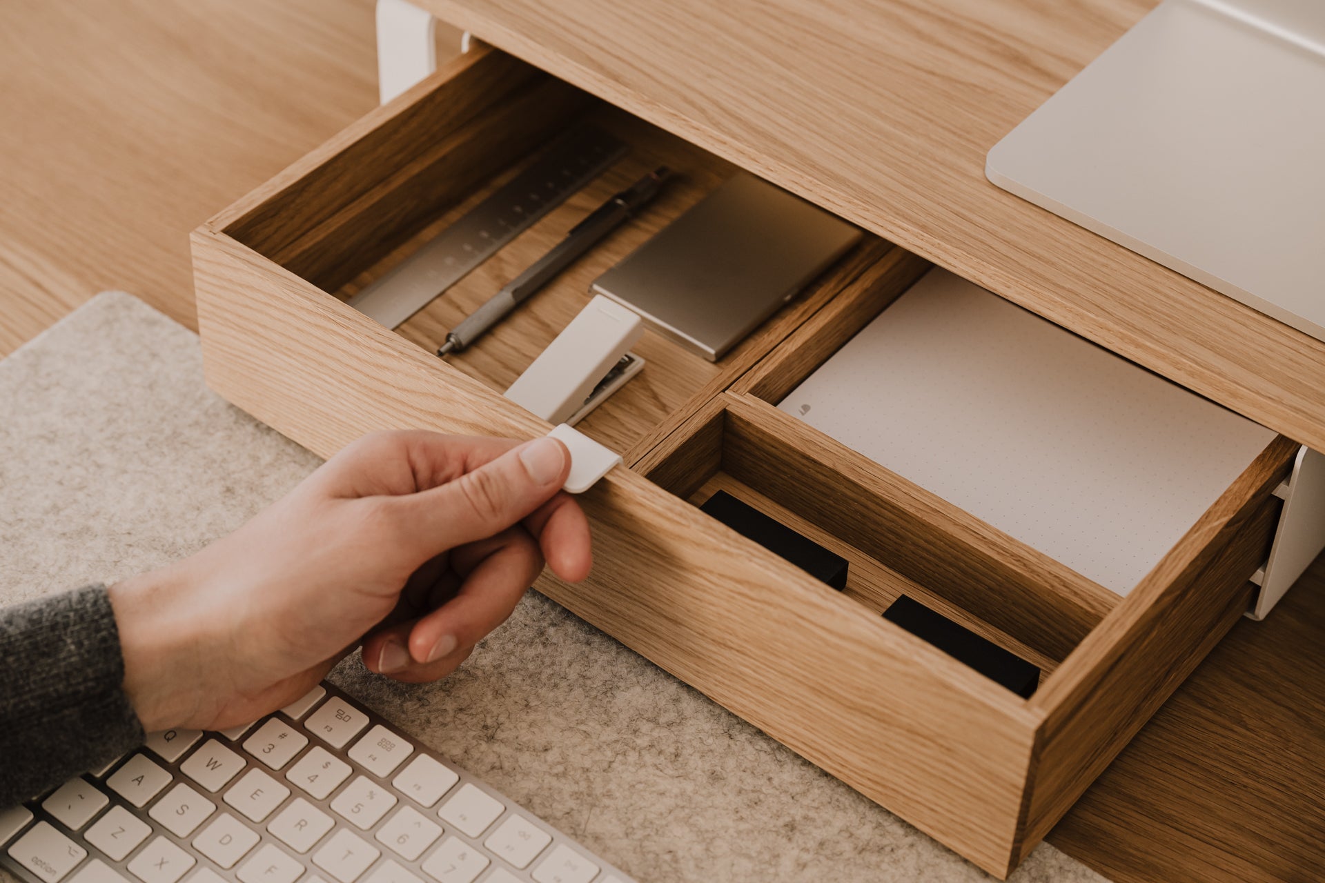 Hand placing a small object into a modular drawer organizer with compartments.| oak, 