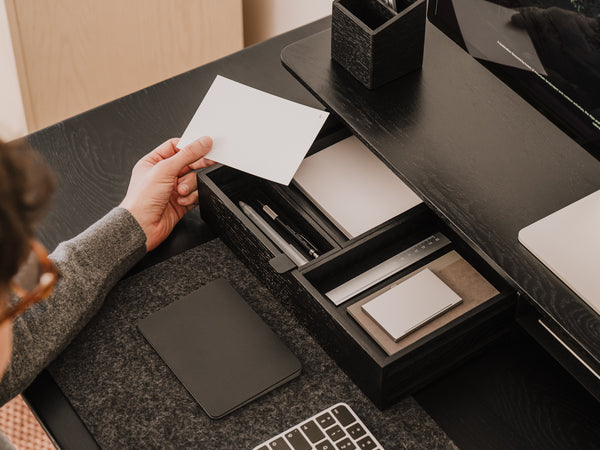 Person organizing items on a desk with a focus on stationery and technology. drawer organisers wood | black, 