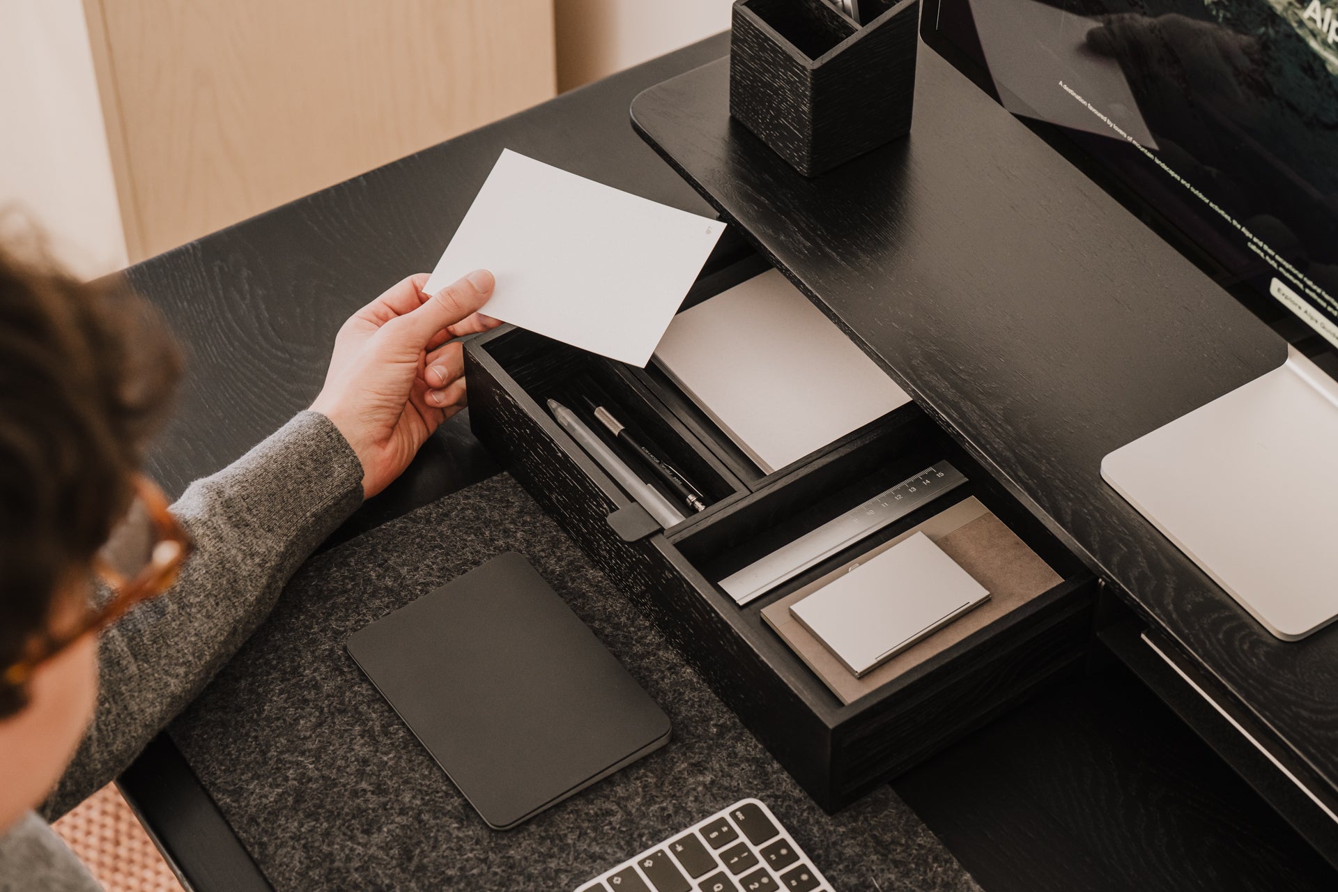 Person organizing items on a desk with a focus on stationery and technology. drawer organisers wood | black, 