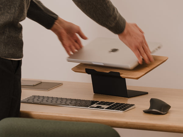 Person using a laptop on a wooden stand at a desk with a keyboard and mouse Oakywood Laptop Riser | oak,