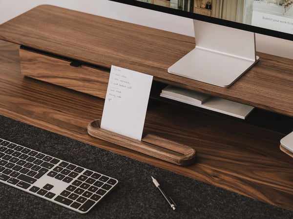 Wooden desk with computer setup including keyboard, monitor, and stationery | walnut