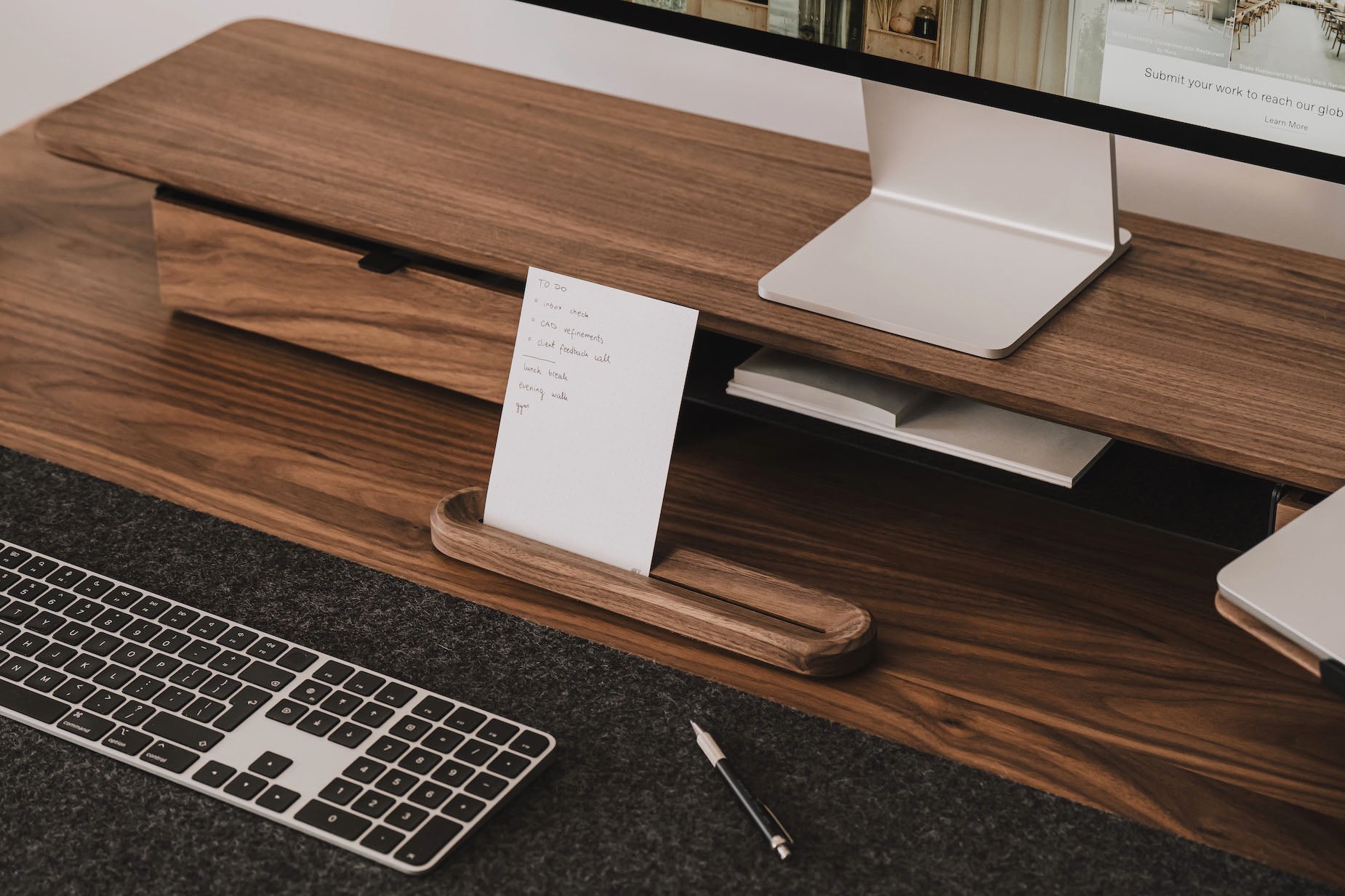Wooden desk with computer setup including keyboard, monitor, and stationery | walnut