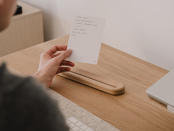 Person holding a paper to-do list at a wooden desk | oak