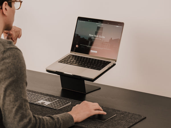 Person using a laptop on a stand at a desk with a minimal background Oakywood Laptop Riser | black,