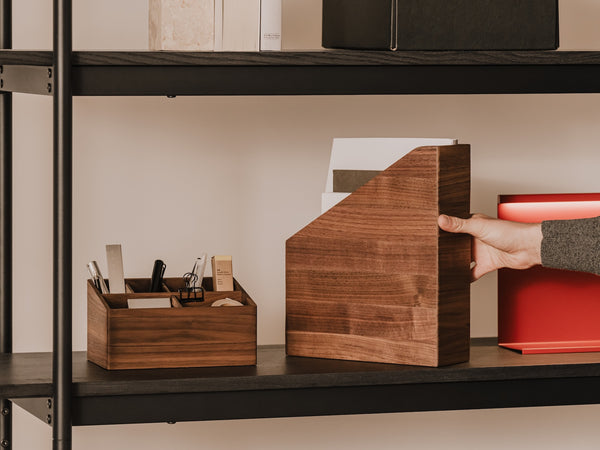 Person arranging wooden A4 paper holder on a shelf with office supplies  | walnut