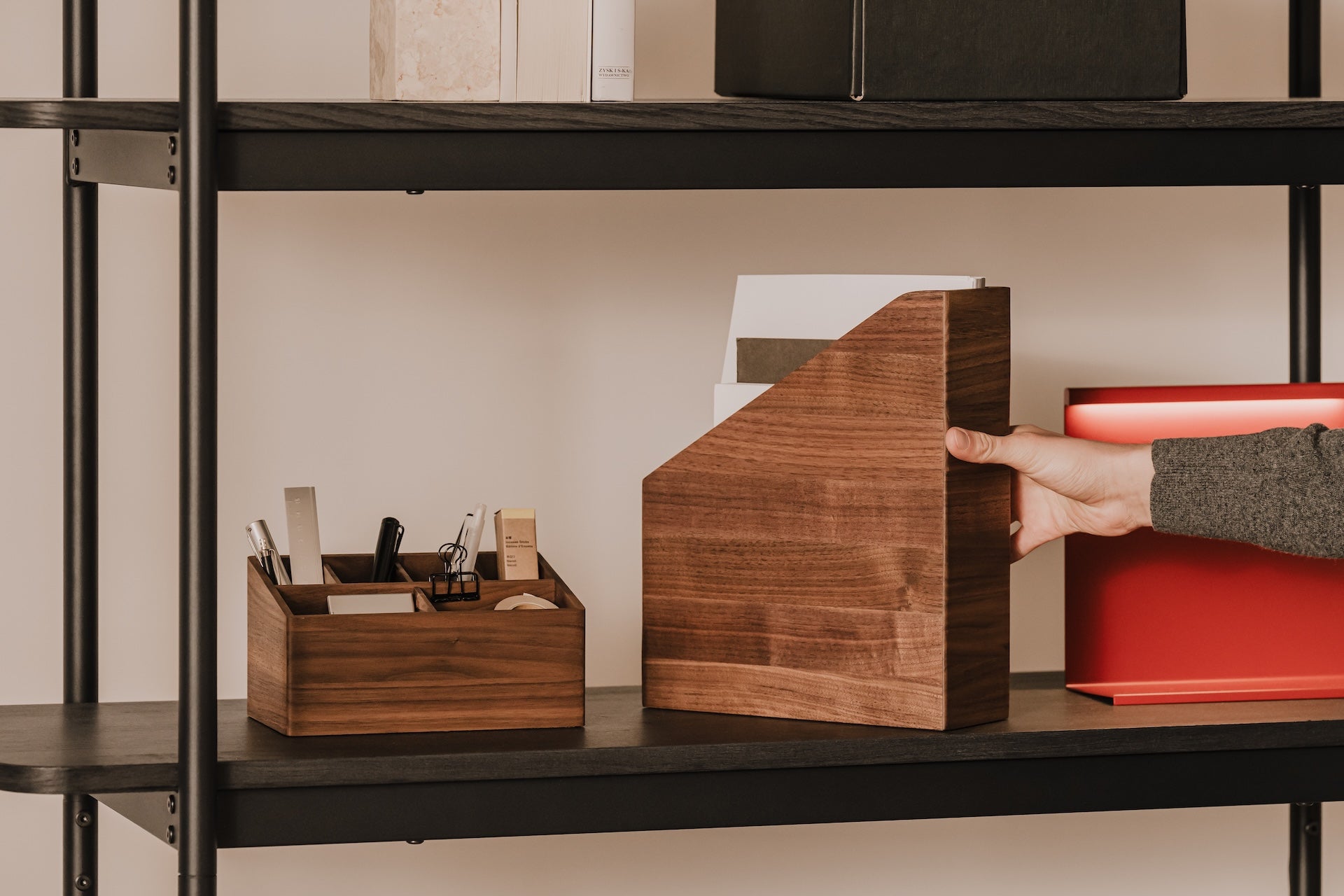 Person arranging wooden A4 paper holder on a shelf with office supplies  | walnut