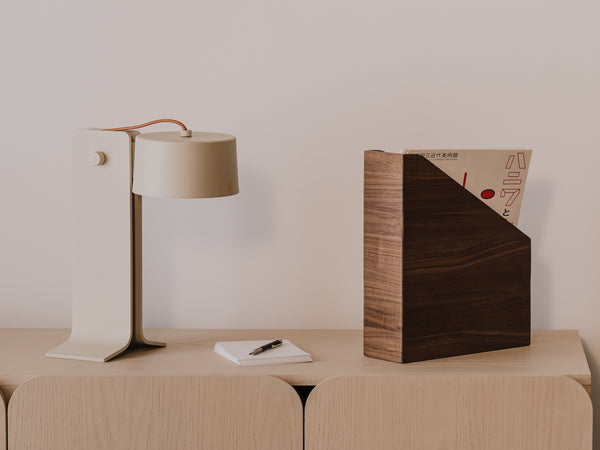 Modern lamp, notebook, and wooden magazine paper holder with a minimalistic background  | walnut