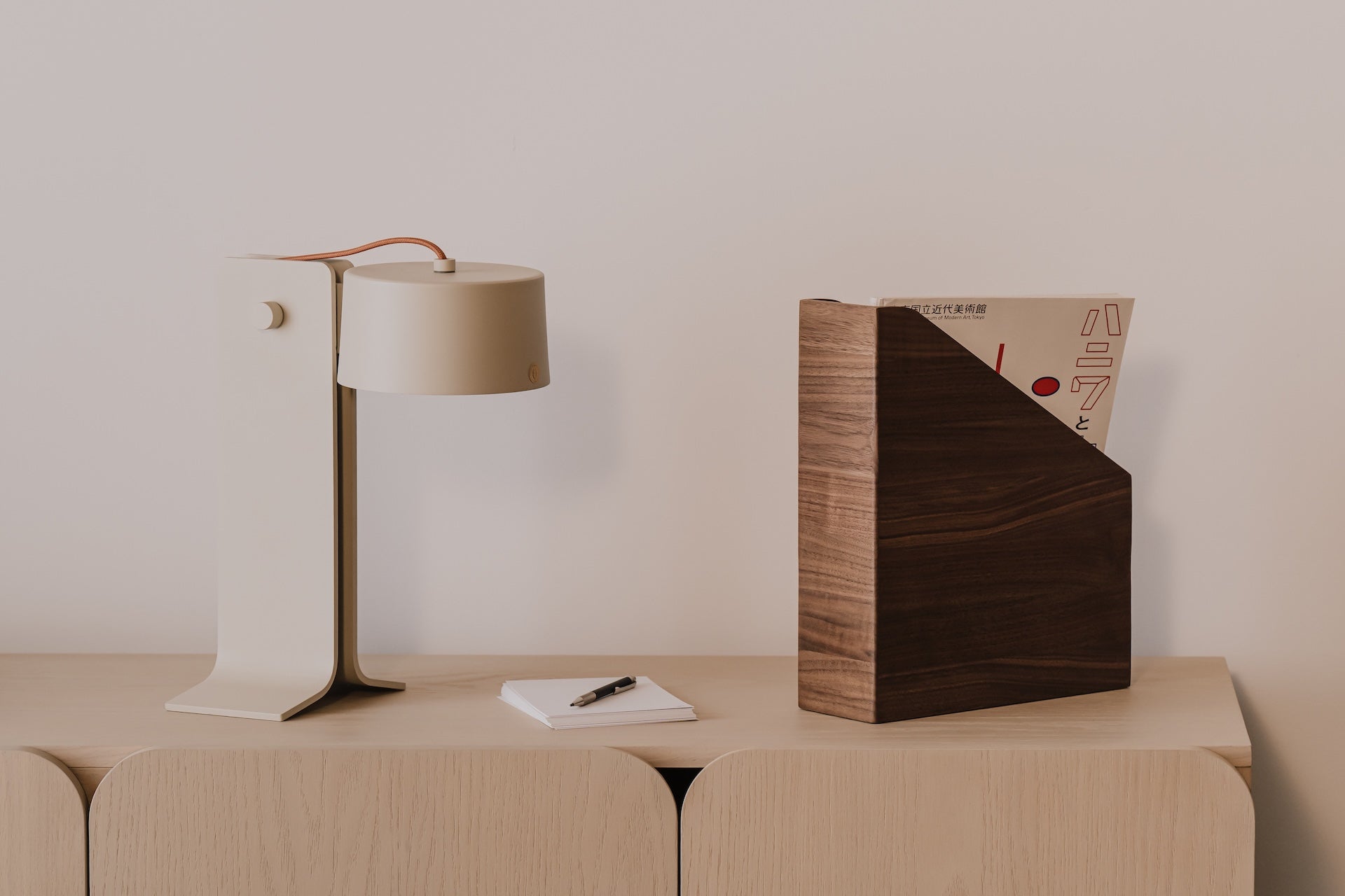 Modern lamp, notebook, and wooden magazine paper holder with a minimalistic background  | walnut