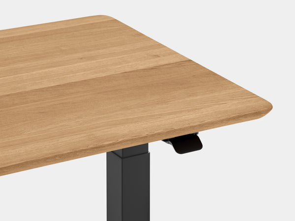 Close-up of white leg joint with height adjustment sections under oak tabletop.