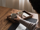 Person holding a ceramic cup on a wooden table with a laptop | walnut, 