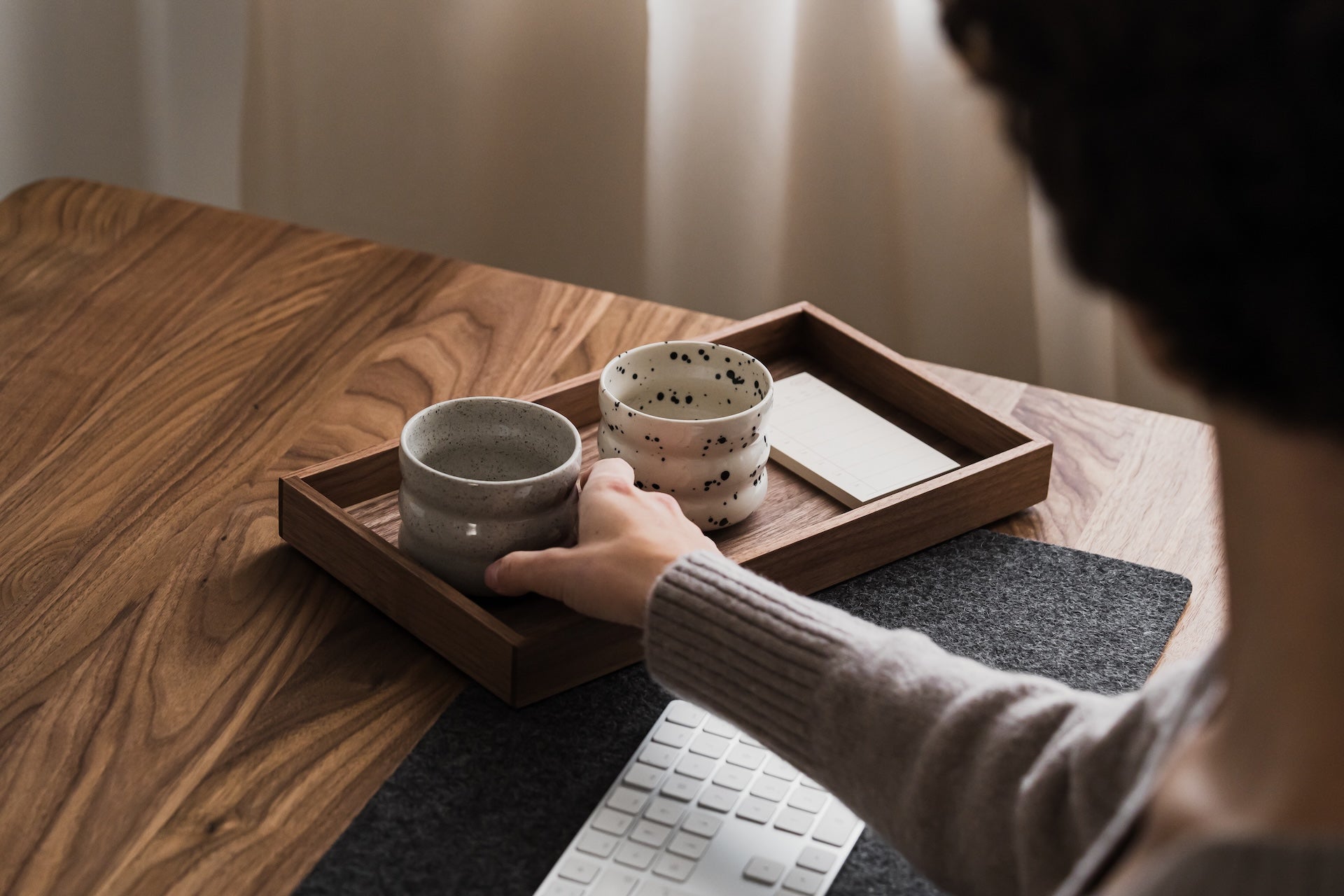 Person holding a ceramic cup on a wooden table with a laptop | walnut, 