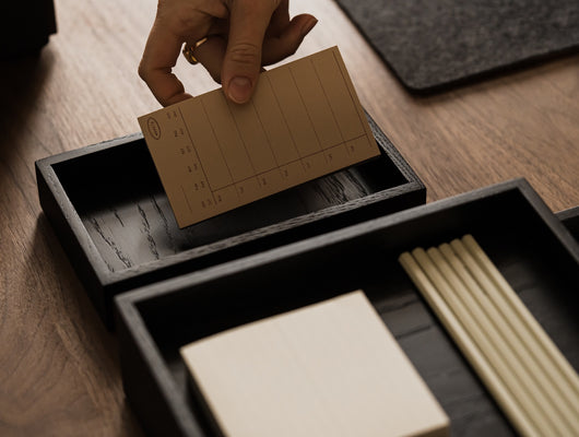 Person placing a brown card into a black Oakywood Valet Tray – stylish black tray for office | black, 
