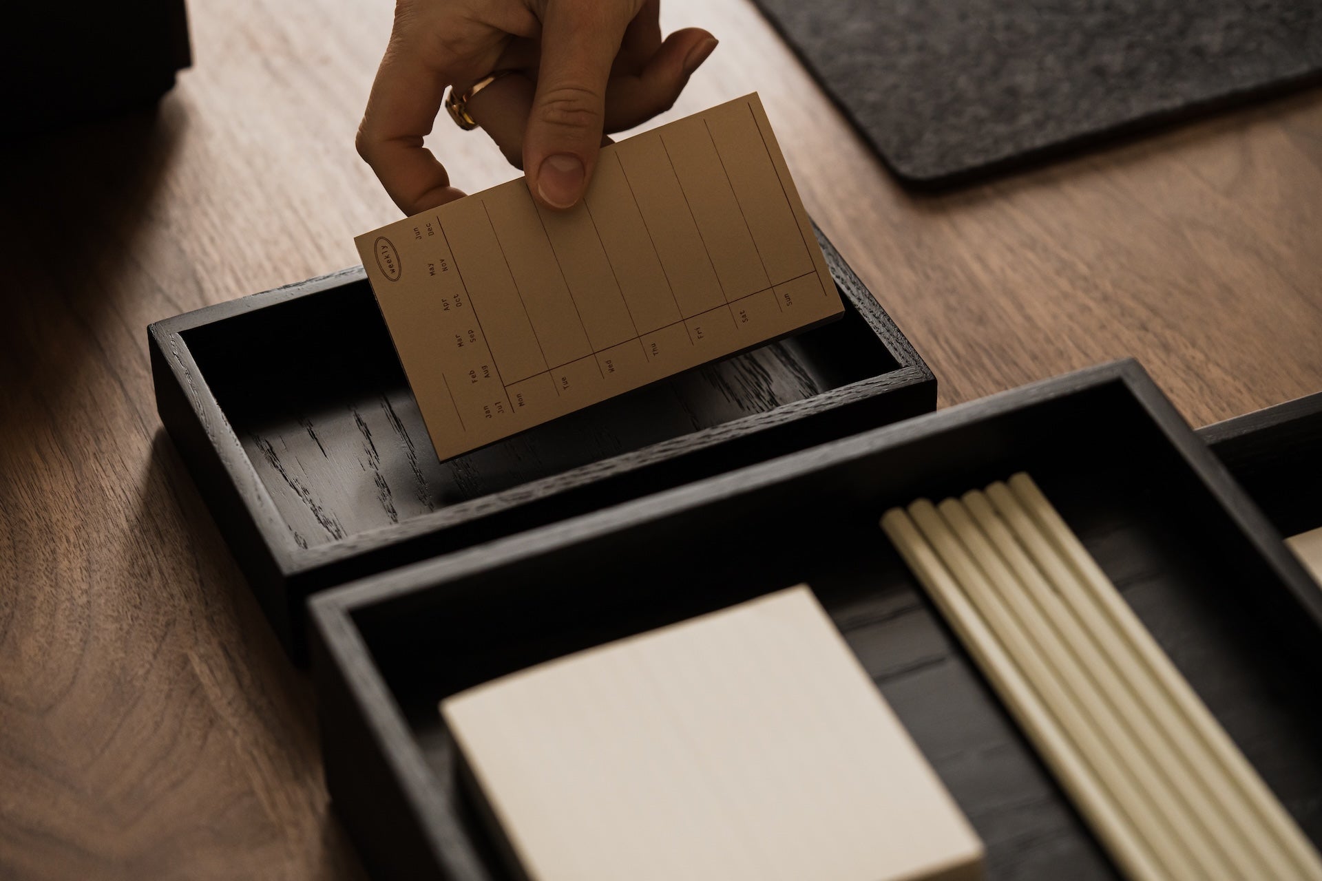 Person placing a brown card into a black Oakywood Valet Tray – stylish black tray for office | black, 
