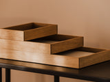 Stackable wooden desk organizer tray on a dark surface against a beige wall | oak, 