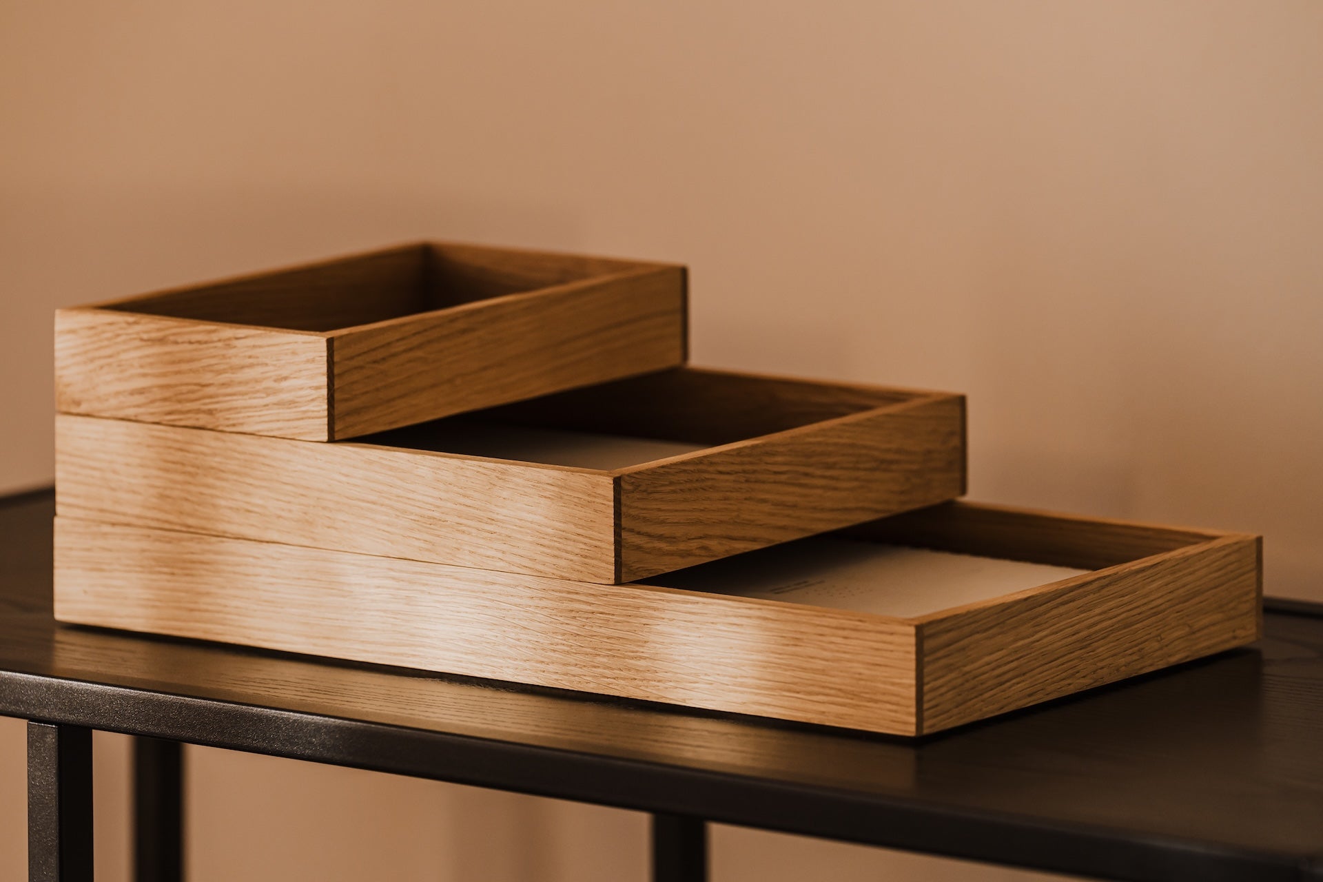 Stackable wooden desk organizer tray on a dark surface against a beige wall | oak, 