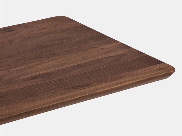 A corner of a dark brown wooden table or shelf with rounded edges